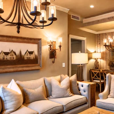 An elegant farmhouse living room with a beautiful farmhouse chandelier and rustic wall sconces. The decor is sophisticated with a mix of modern and fa